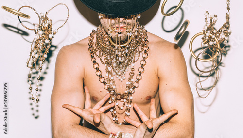 a man  with golden jewelry and a black hat photo