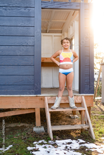 Girl in swimsuit and snowboots in snowy yard