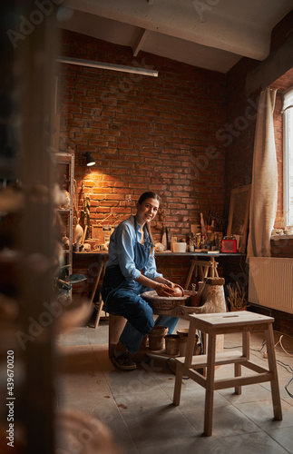 Young Caucasian ceramicist shaping clay pot in pottery workshop