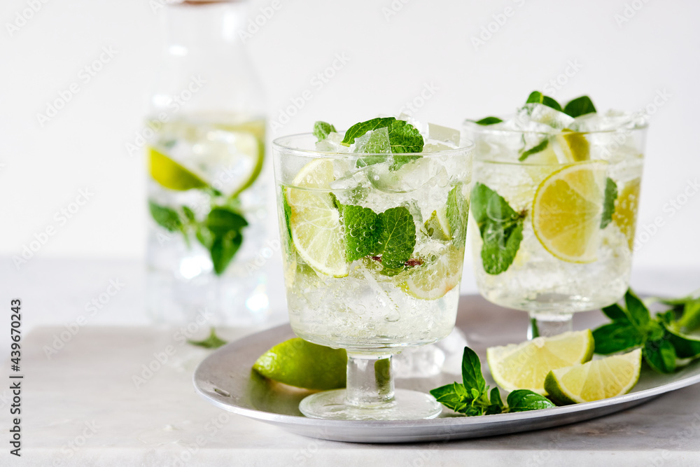 Cold refreshing summer lemonade mojito in a glass on a grey concrete or stone background. Copy space. Cold refreshing summer lemonade mojito in a glass on a grey concrete or stone background. Copy space.