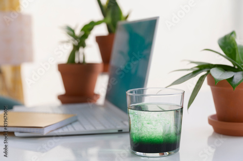 Glass of Water with Chlorophyll at Green Workspace photo