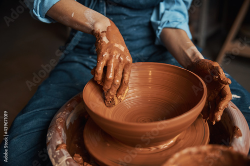 Beautiful elegant female artisan hands shaping clay tableware in pottery workshop