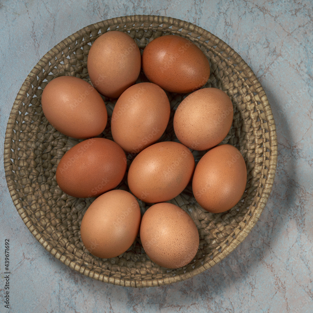 several fresh chicken eggs in a straw basket on a wooden background. Healthy eating concept. several fresh chicken eggs in a straw basket on a wooden background. Healthy eating concept.