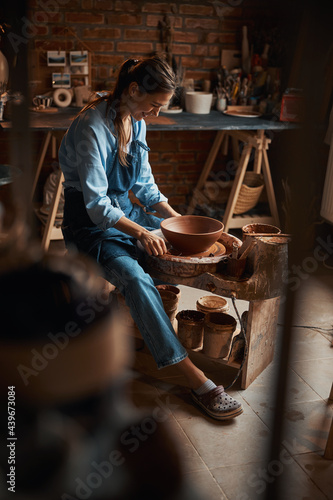 Beautiful elegant female artisan shaping tableware in art home studio