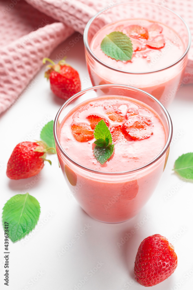 Fresh strawberry milkshake decorated with berries and mint on a light background in pastel colors, space for text, the concept of a healthy breakfast, diet and good nutrition. Fresh strawberry milkshake decorated with berries and mint on a light background in pastel colors, space for text, the concept of a healthy breakfast, diet and good nutrition.