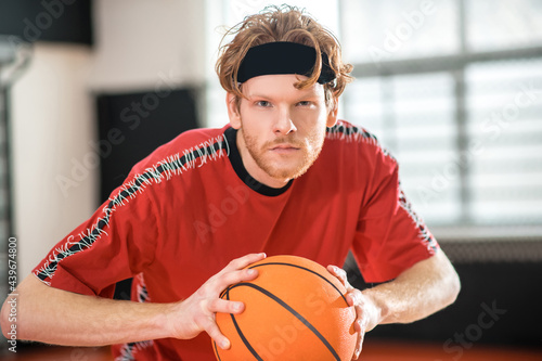 Ginger man in a red sportswear playing basketball