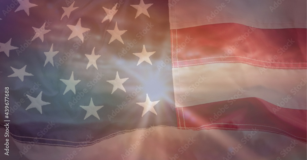 Fototapeta premium Composition of american flag billowing over setting sun and sky