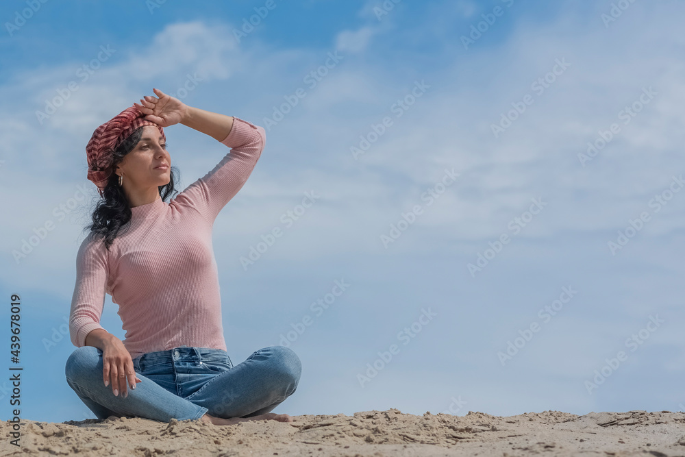 .Girl sitting on the sand under the blue sky and smiling .Girl sitting on the sand under the blue sky and smiling