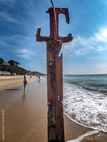 Canford Cliffs beach in Dorset on a sunny day. Rusting metal post in foreground with blue sea and coastline in the background.  Dorset beach in the UK near Poole Harbour.