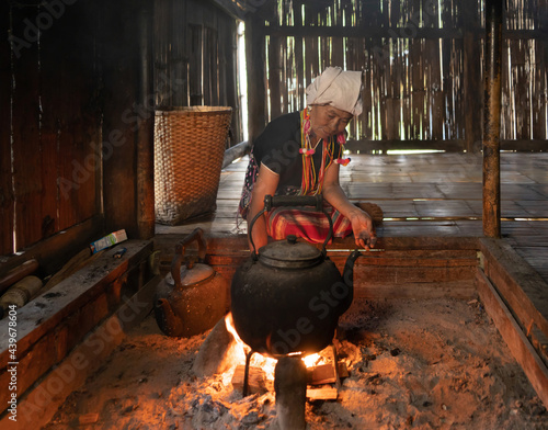 Canvas-taulu A portrait of karen tribe woman boiling water by using traditional kettle and fire, water heater at wooden kitchen at local home