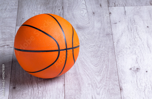 Orange basketball ball on wooden parquet. Close-up image of basketball ball over floor in the gym © Александр Бердюгин