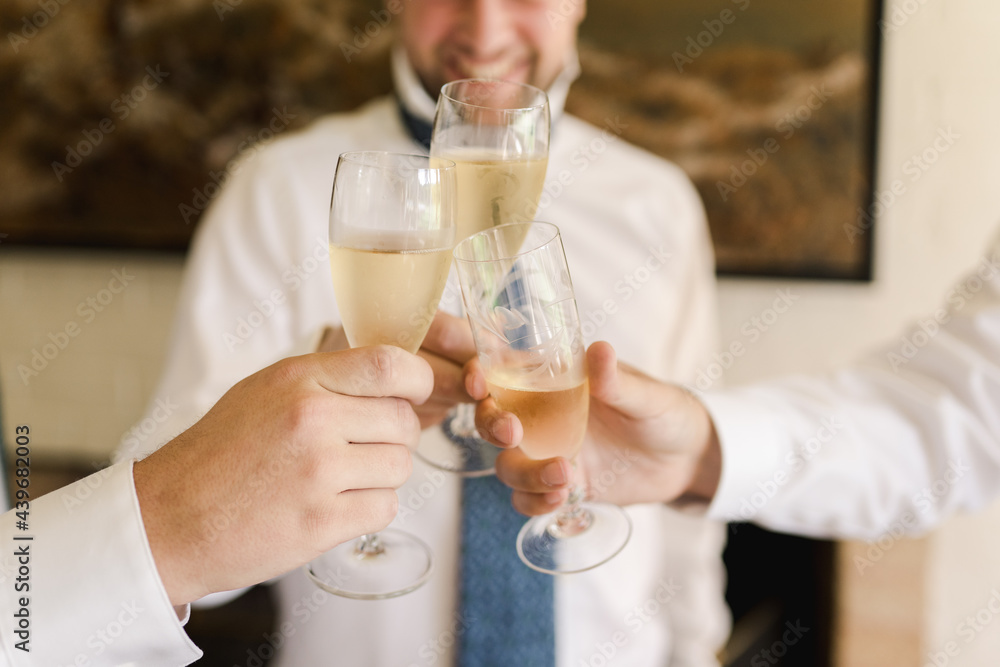 groom holding champagne glasses with his groomsmen groom holding champagne glasses with his groomsmen