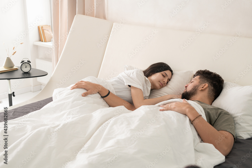 Fototapeta premium Amorous couple sleeping peacefully in bed in hotel room