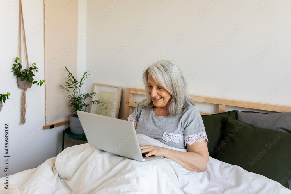 relax mature woman with laptop on bed relax mature woman with laptop on bed