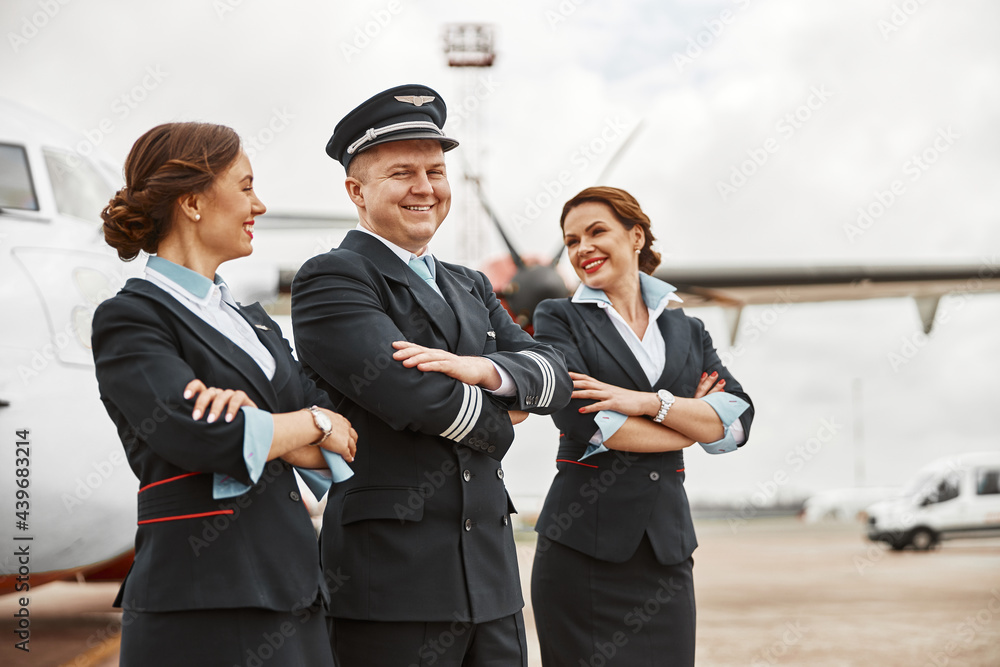 Pilot and stewardesses on runway near airplane jet