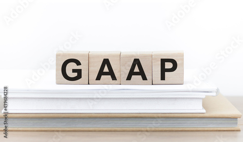 Generally Accepted Accounting Practice. GAAP the word on wooden cubes on a stack of books on the table.