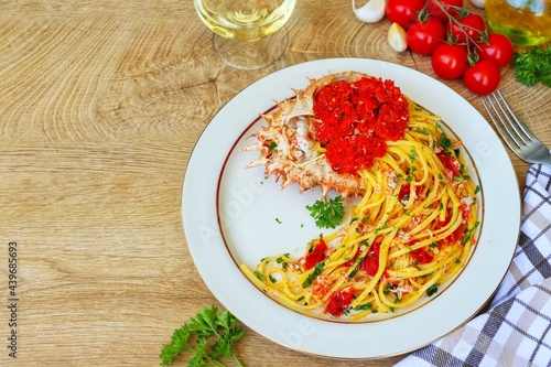 Photos Italian Traditional DishTagliolini alla granseola,spaghetti with spider crabs,cherry tomatoes,olive oil,white wine,parsley,garlics,salt and peppers on plate with wooden table background