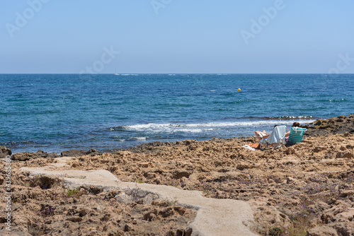 Cement path on a rocky beach where two people sunbathe in hammocks, Javea, Alicante, Spainn photo