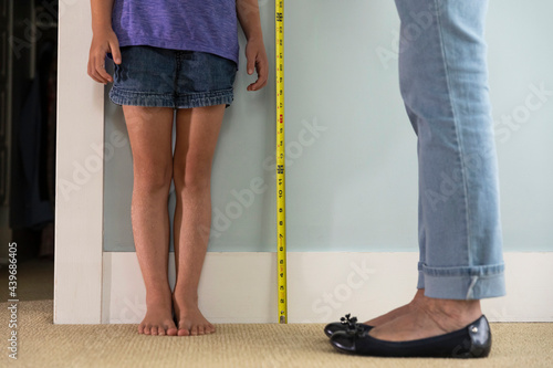 Barefoot Young Girl Measuring her height with just legs showing  photo