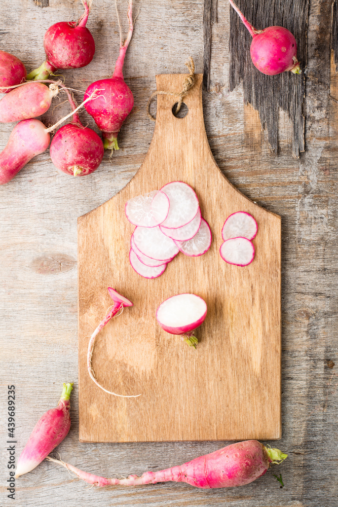 Fresh sliced radish on a cutting board on a wooden table. Vegetables for a vegetarian diet. Rustic style. Top and vertical view