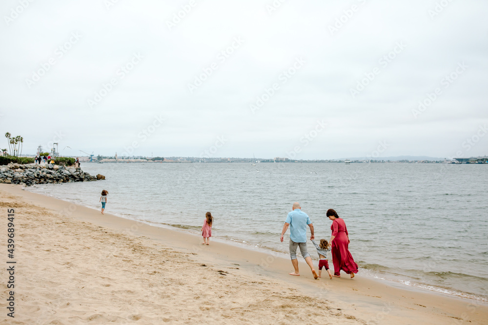 Young boy walking between parents on beach Young boy walking between parents on beach