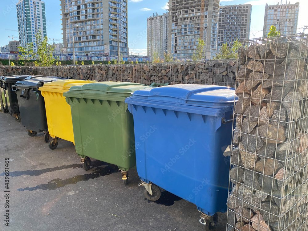 Black, yellow, green and blue plastic large modern containers for separate collection and subsequent ecological recycling of waste in a new area of the city Black, yellow, green and blue plastic large modern containers for separate collection and subsequent ecological recycling of waste in a new area of the city
