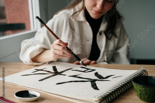 Young woman writing japanese kanji characters with a brush and ink photo