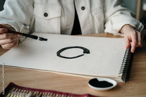 Young woman writing japanese kanji characters with a brush and ink