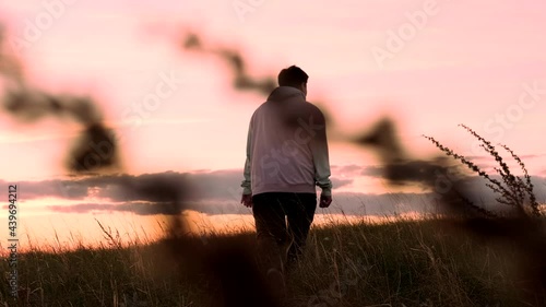 Young lonely guy walks at sunset. Evening time of day