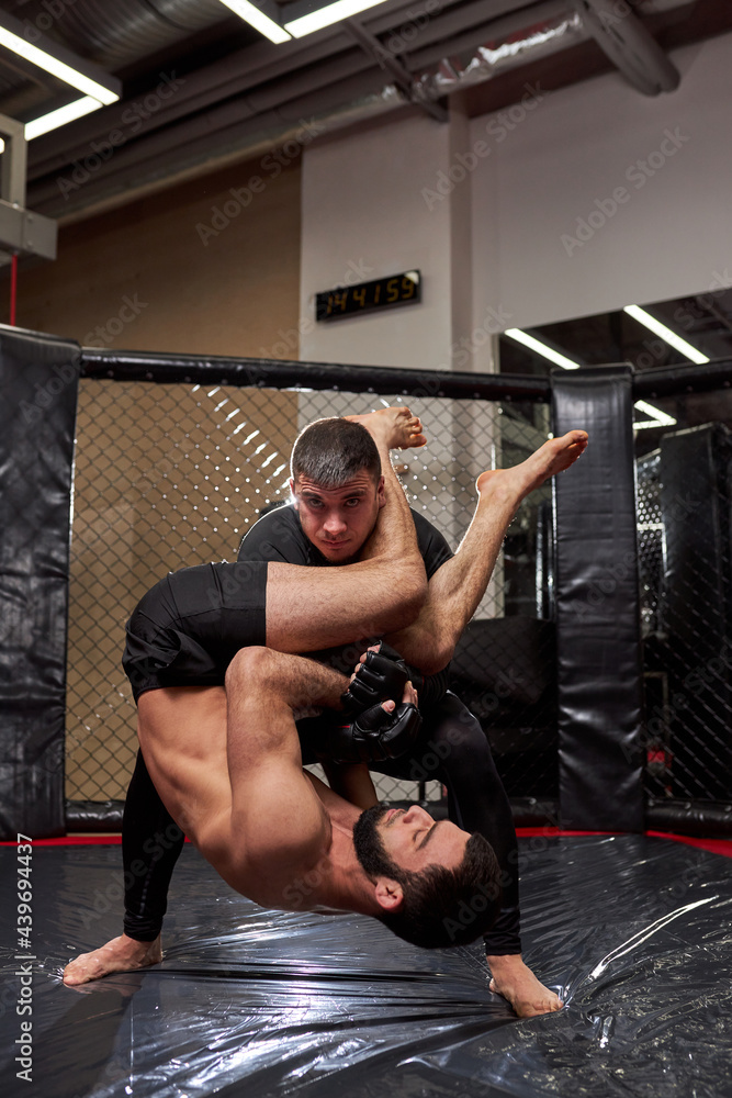 Sports concept of fighting without rules. Two athlete wrestlers at gym, training together. fights without boxing rules MMA. sporting battles side view Sports concept of fighting without rules. Two athlete wrestlers at gym, training together. fights without boxing rules MMA. sporting battles side view