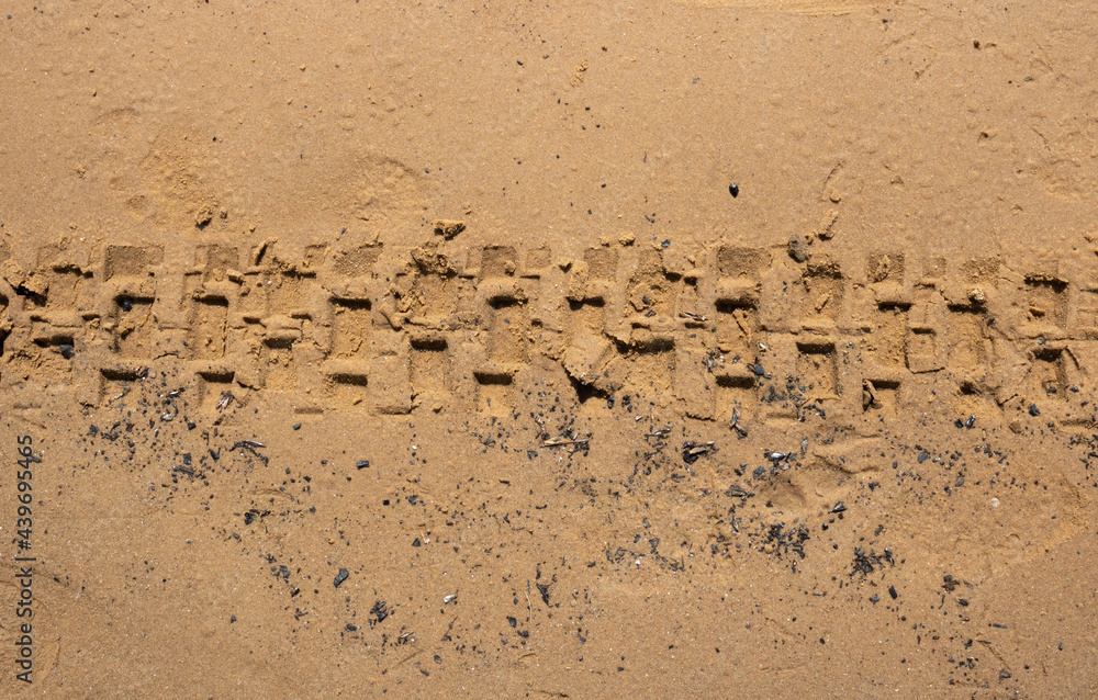 The texture of wet brown sand with traces of bicycle tires The texture of wet brown sand with traces of bicycle tires
