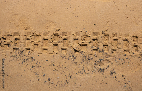 The texture of wet brown sand with traces of bicycle tires