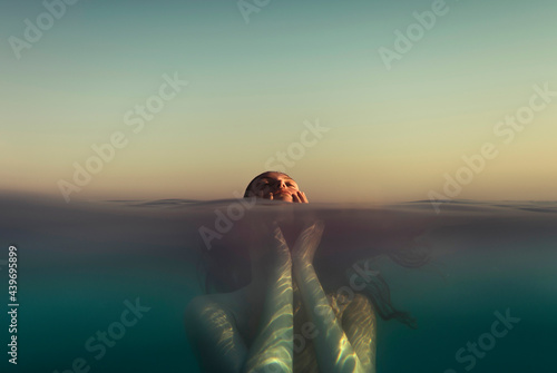 Woman holding her face in the sea