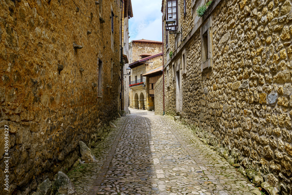 Narrow alley with old stone houses and arches of medieval buildings. Santillana del Mar.