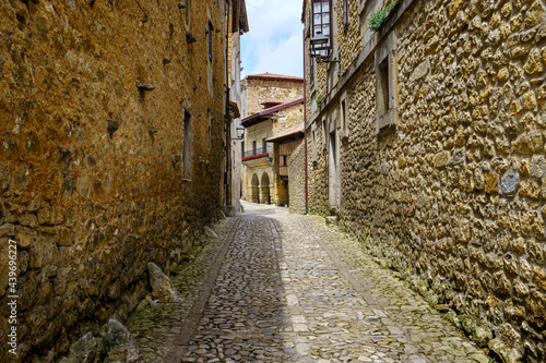 Fototapeta Naklejka Na Ścianę i Meble -  Narrow alley with old stone houses and arches of medieval buildings. Santillana del Mar.