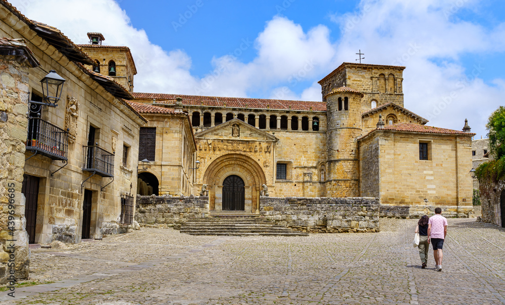 Couple of people walking in an old stone town with a Romanesque church in Santillana del Mar, Santander.