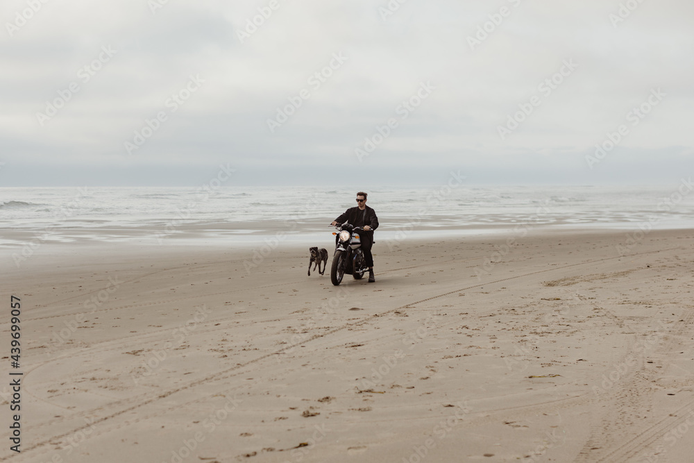 Trendy man riding Motorcycle on Beach with dog Trendy man riding Motorcycle on Beach with dog