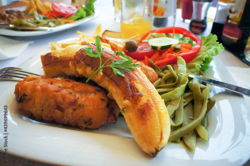 Fish espada with fried banana, french potatoes, kidney beans and fresh vegetables. Fish espada with fried banana, french potatoes, kidney beans and fresh vegetables.