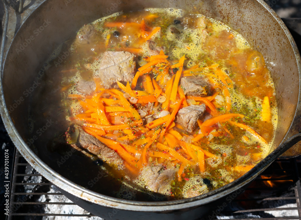 Cooking traditional oriental pilaf in a cauldron over a fire. Cooking traditional oriental pilaf in a cauldron over a fire.