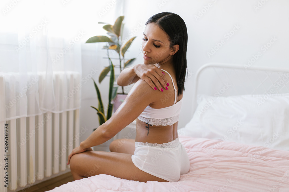 Beautiful black woman applying cosmetic lotion on her body Beautiful black woman applying cosmetic lotion on her body