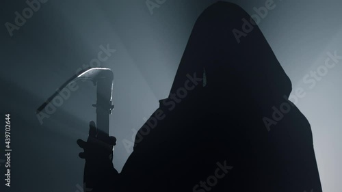 Silhouette death with scythe indoors. Man in costume grim reaper on halloween . photo