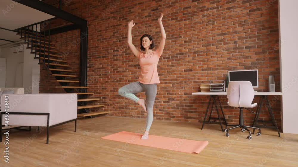 caucasian woman in sportswear standing on yoga mat tree pose stretching fitness in apartment caucasian woman in sportswear standing on yoga mat tree pose stretching fitness in apartment