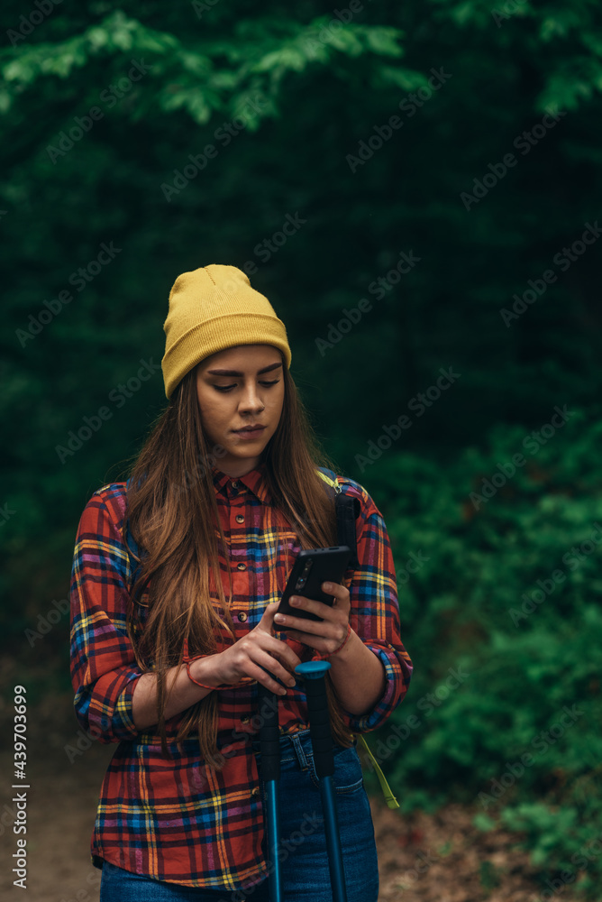 Woman hiking in the nature and using smartphone for easy orientation