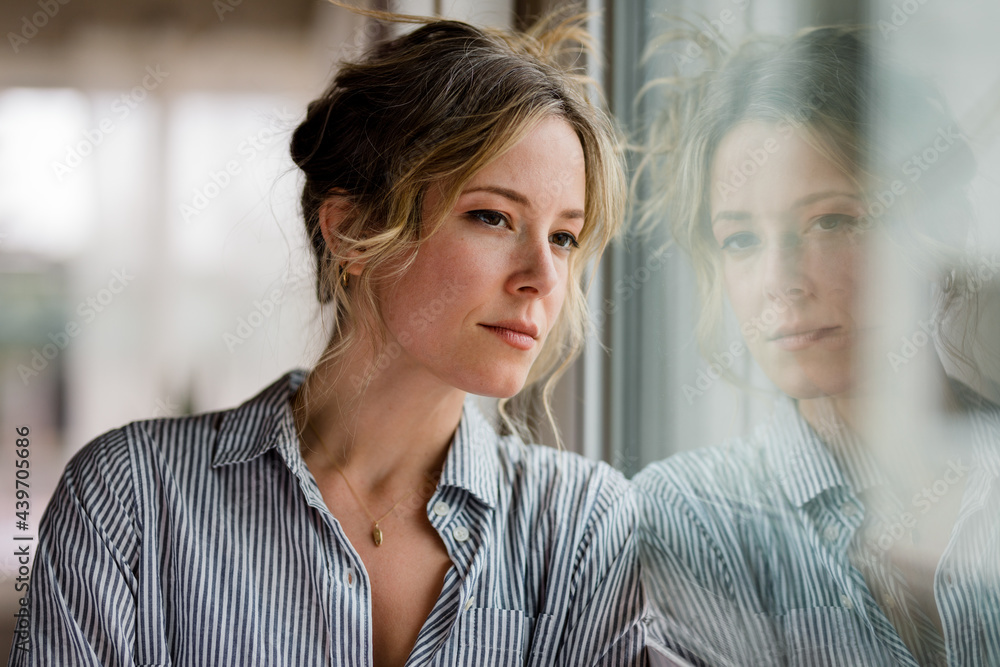 Young Woman Stares Out the Window of Her Apartment. Young Woman Stares Out the Window of Her Apartment.