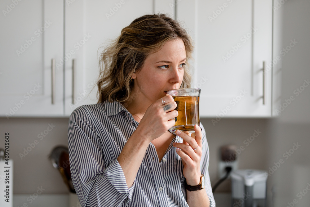 Beautiful Woman Sips Tea While Staring Out Kitchen Window Beautiful Woman Sips Tea While Staring Out Kitchen Window
