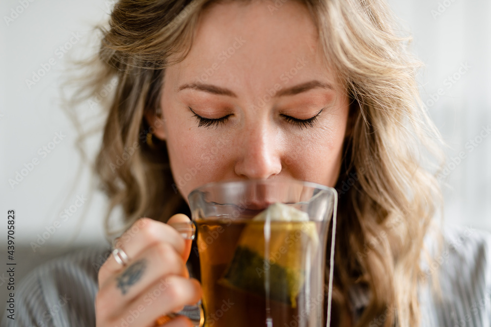 Relaxed Woman Drinks Hot Tea From a See-Through Mug Relaxed Woman Drinks Hot Tea From a See-Through Mug