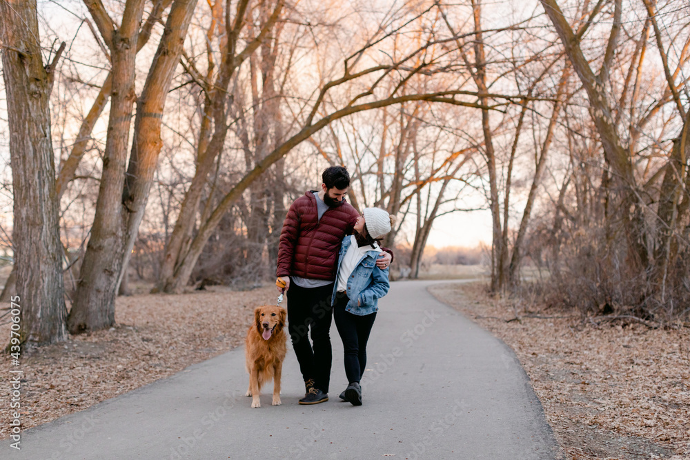 Happy Couple Walking Dog in Park