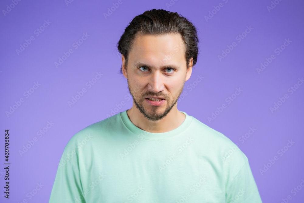 Angry stressed man isolated over purple background. Depressed guy looking to camera with aggression. Angry stressed man isolated over purple background. Depressed guy looking to camera with aggression.