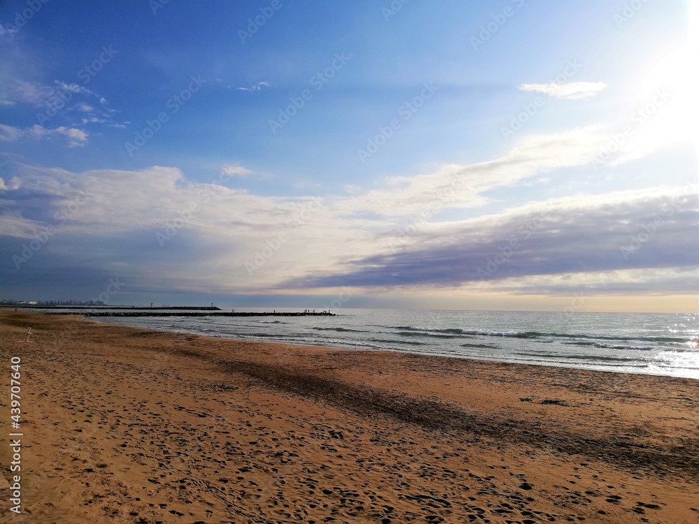 cielo azul con nubes blanquecinas y arena de playa rojiza