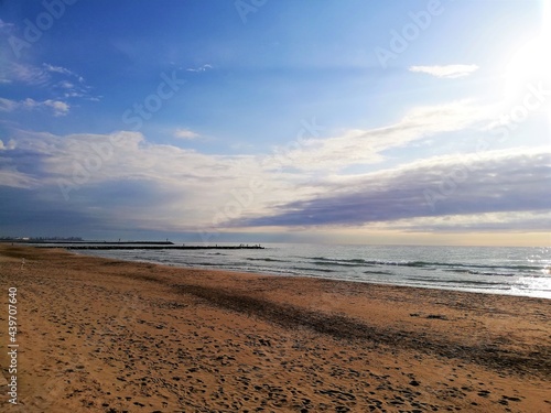 cielo azul con nubes blanquecinas y arena de playa rojiza